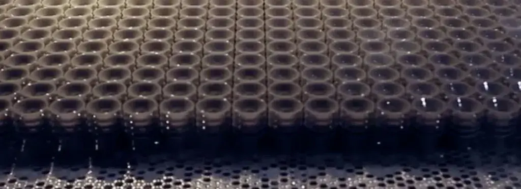 A row of 3D printed plastic bottles emerging from a 3D printer